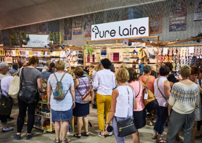 A crowd of shoppers at a booth labeled "Pure Laine."