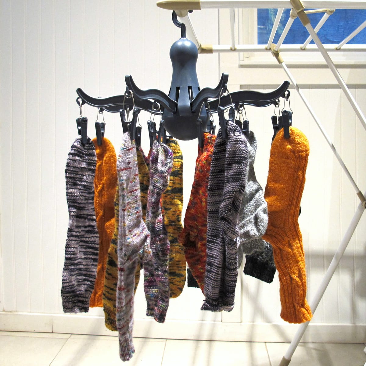 Image description: Several pairs of socks hanging by clips from a multi-pronged round hanger.