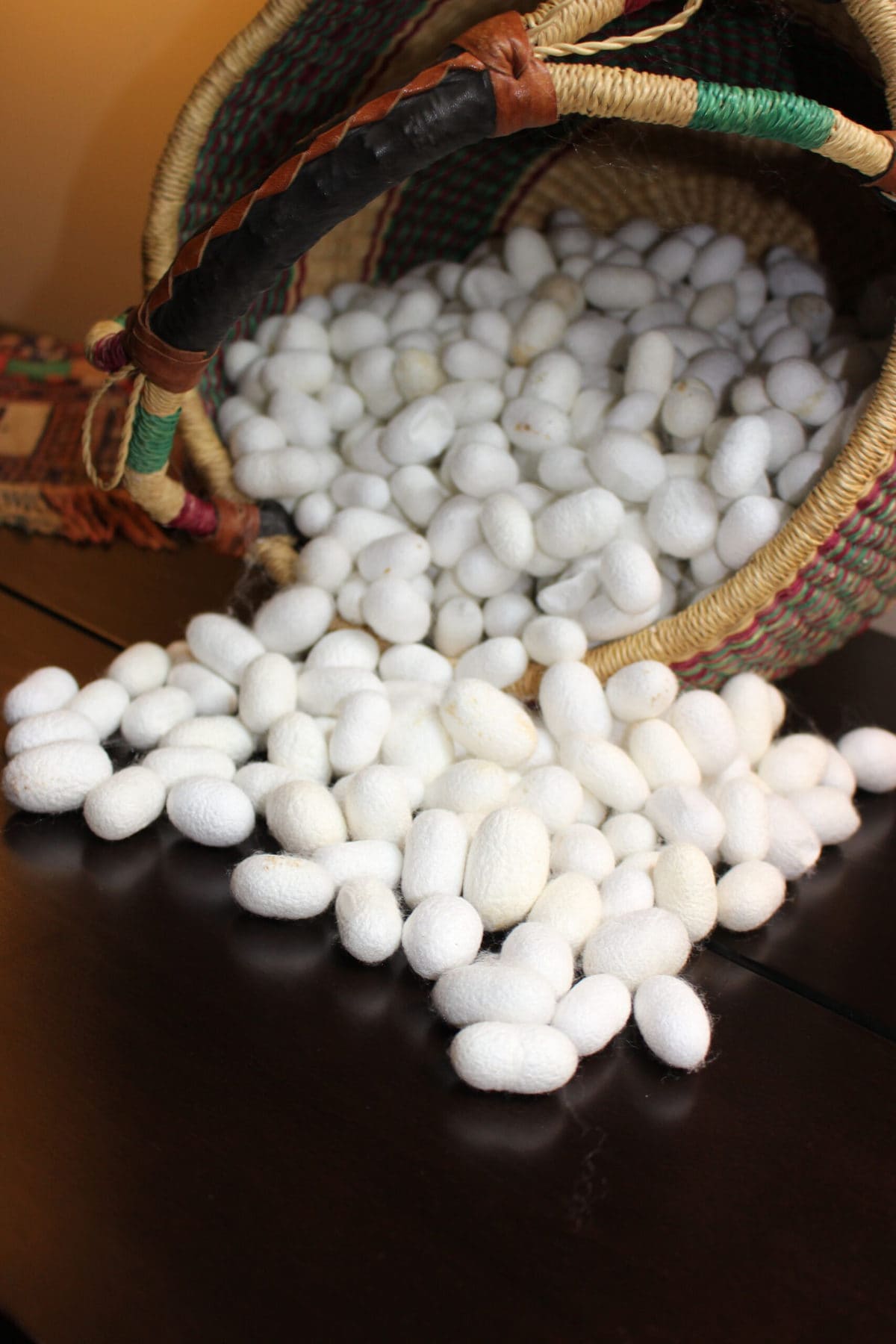 image descriptions: many silk cocoons, tumbling out of a basket