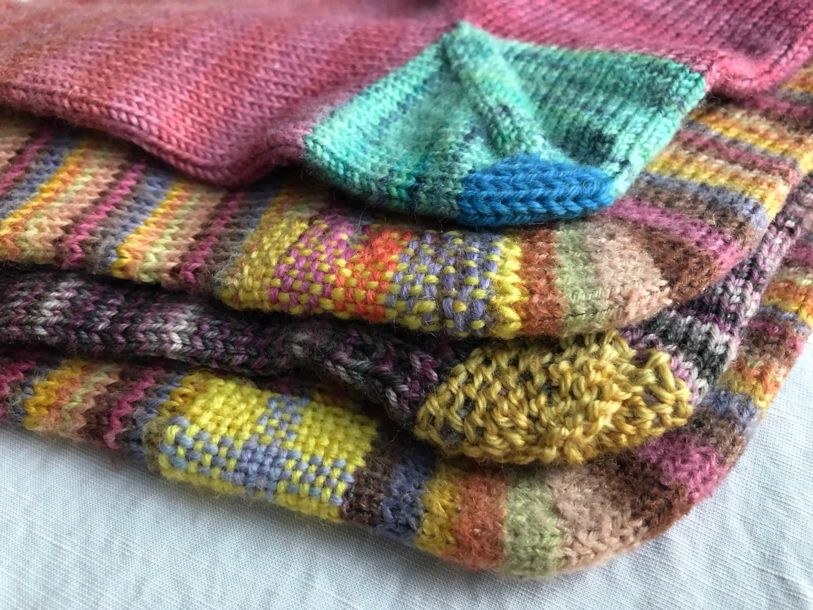 image description: a pile of handknit socks, with evident mends
