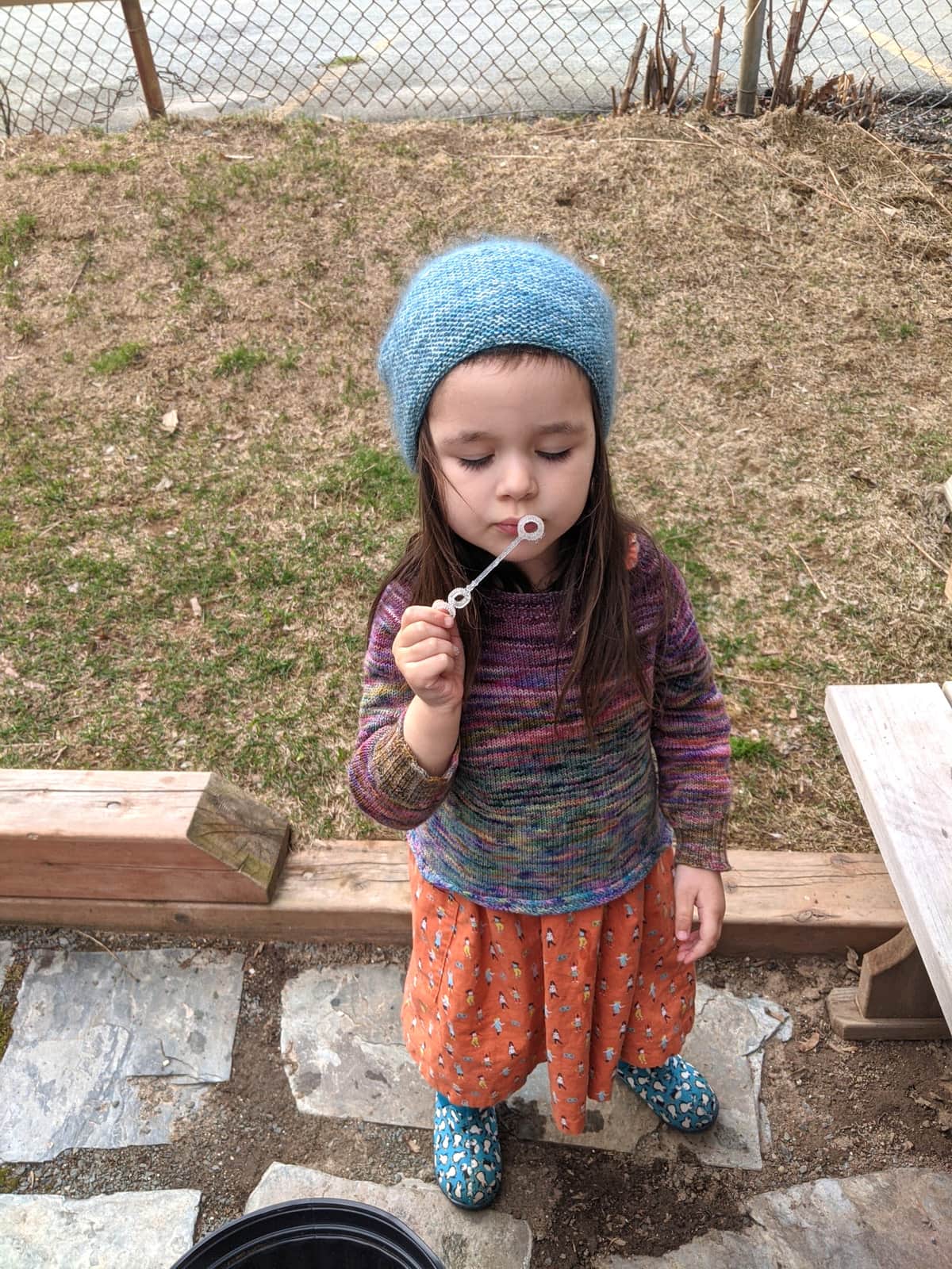 image description: a young child wearing a handknit hand and sweater
