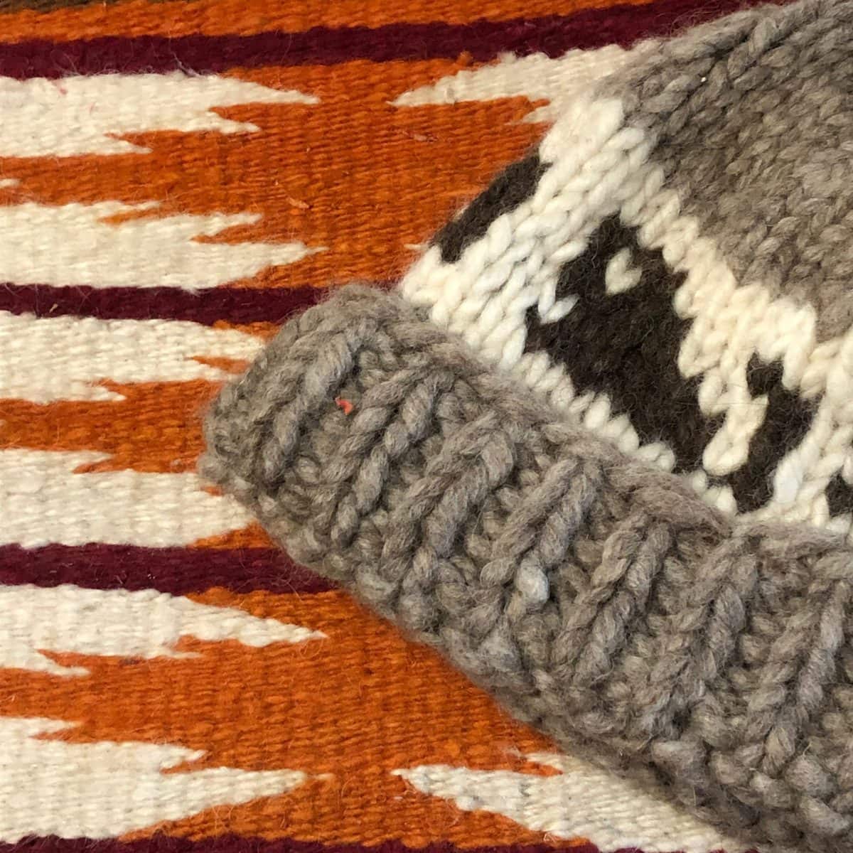 image description: a close up of a Navajo woven cloth and a hat knitted in the Salish style