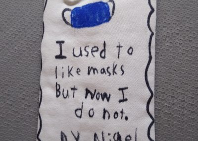 image description: a handmade fabric mask, a message handwritten on it in marker pen