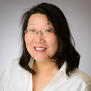image description: image description: a portrait of an Asian woman with shoulder length hair, wearing glasses; she looks direction into the camera