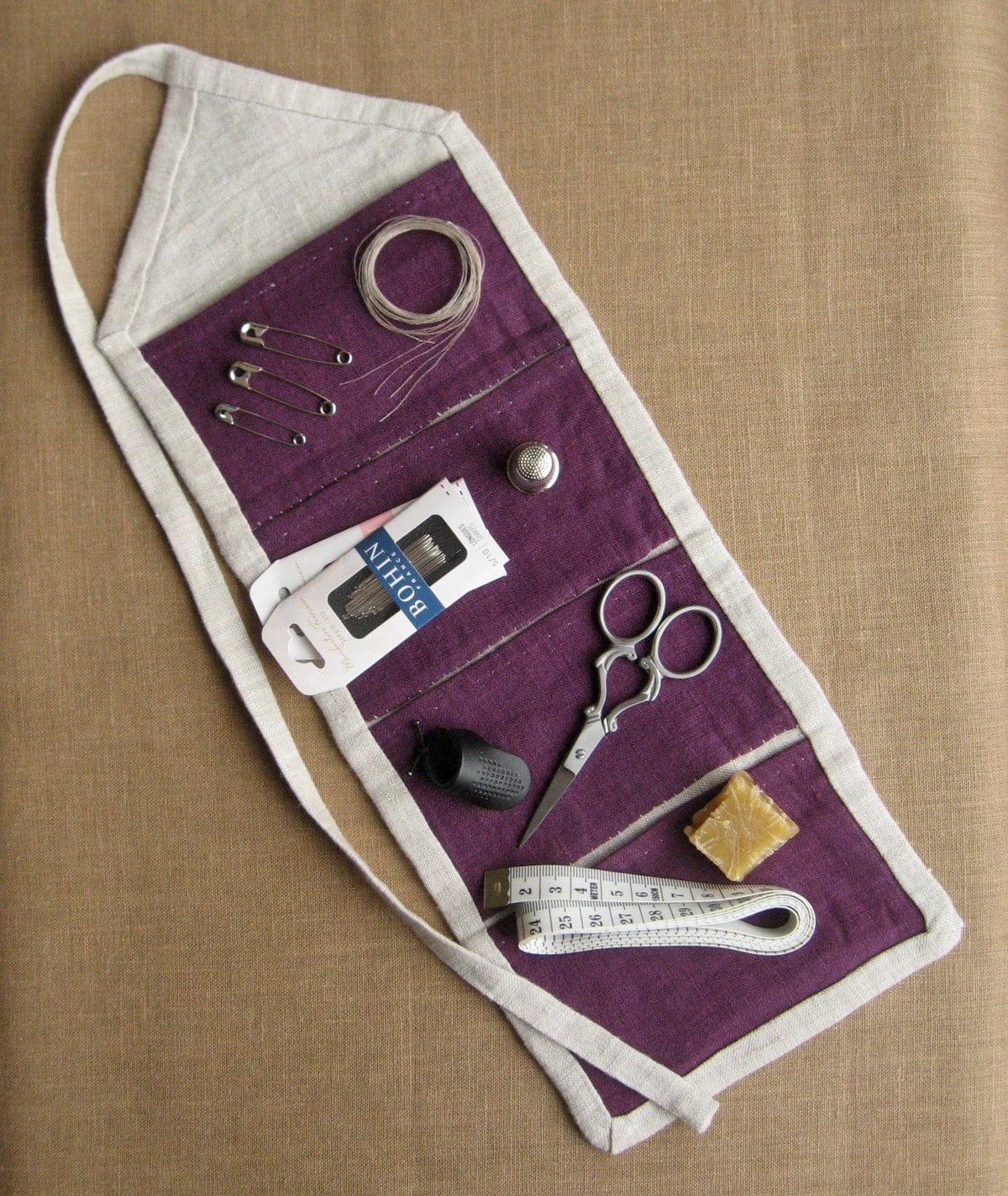 image description: a handsewn fabric pouch with multiple pockets; various sewing tools sit on top